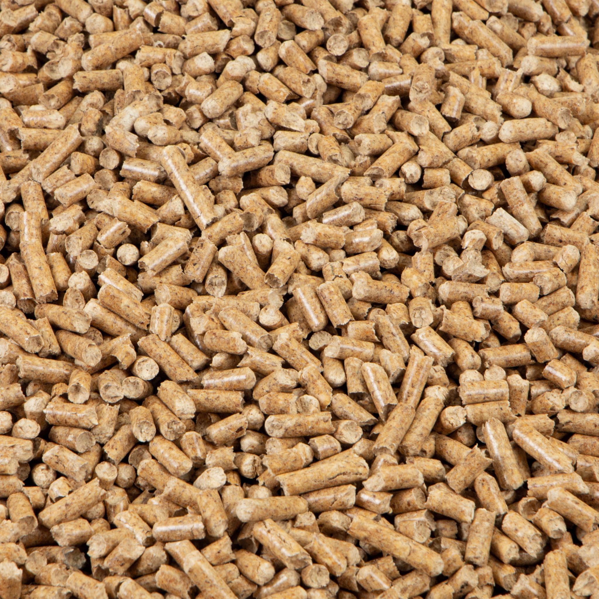 Gęsto ułożone, jasnobrązowe granulki pelletu drzewnego, widoczne drobne włókna drewna i ślady po procesie produkcji.