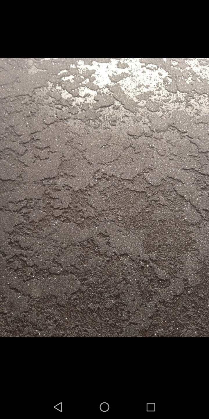 Szara, dekoracyjna struktura ściany z efektem metalicznego połysku w górnej części.