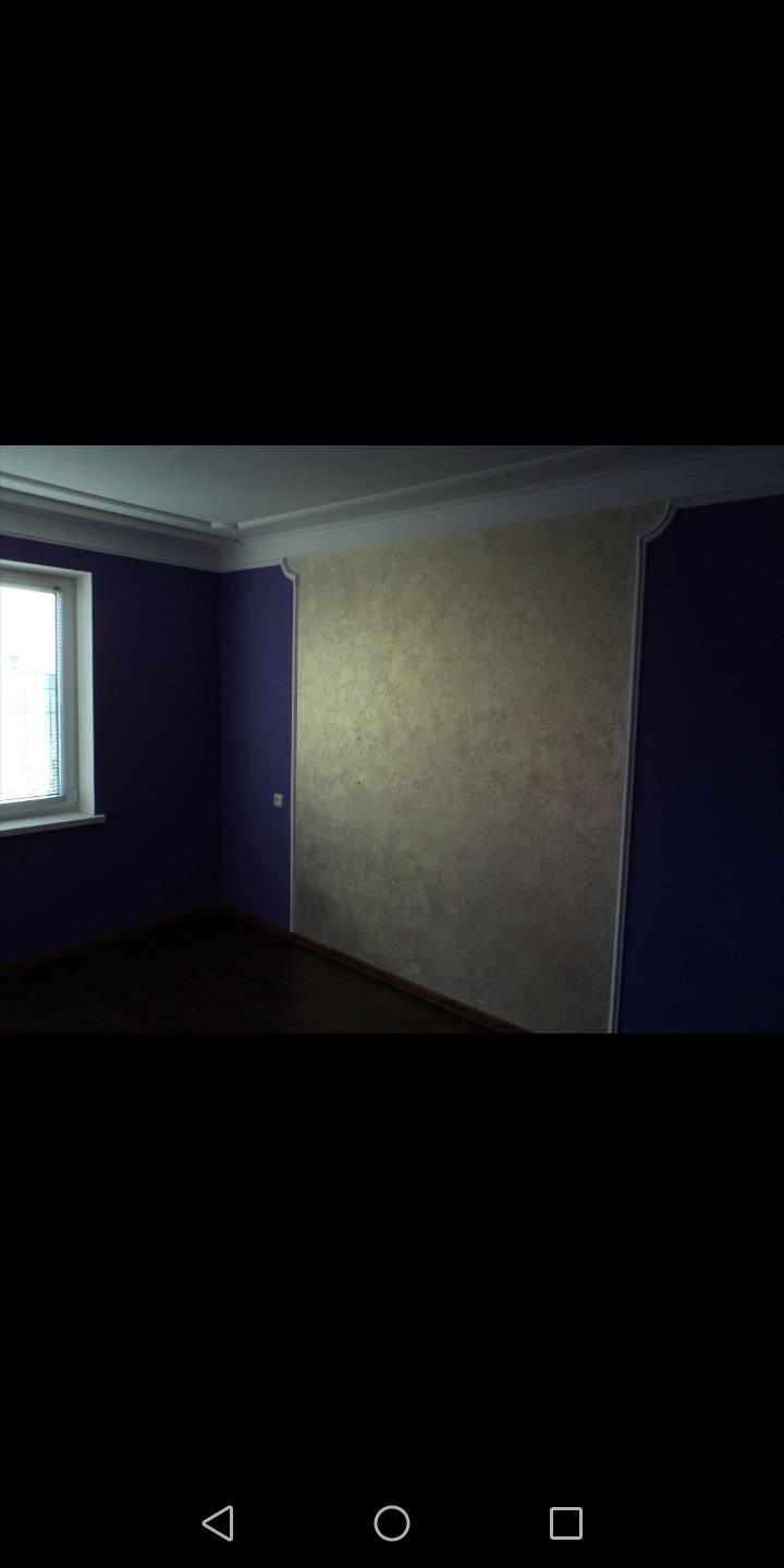 Pokój po remoncie z ciemnymi panelami podłogowymi i ścianami w dwóch kolorach: fioletowym i beżowym z dekoracyjną strukturą, oddzielonymi ozdobnym białym obramowaniem.