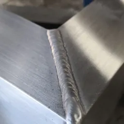 Precyzyjne spoiny na aluminiowym profilu zamkniętym, widoczne delikatne ślady obróbki.