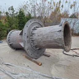 Duży, metalowy element rurowy z kołnierzami, prawdopodobnie po piaskowaniu, leżący na folii ochronnej na zewnątrz.