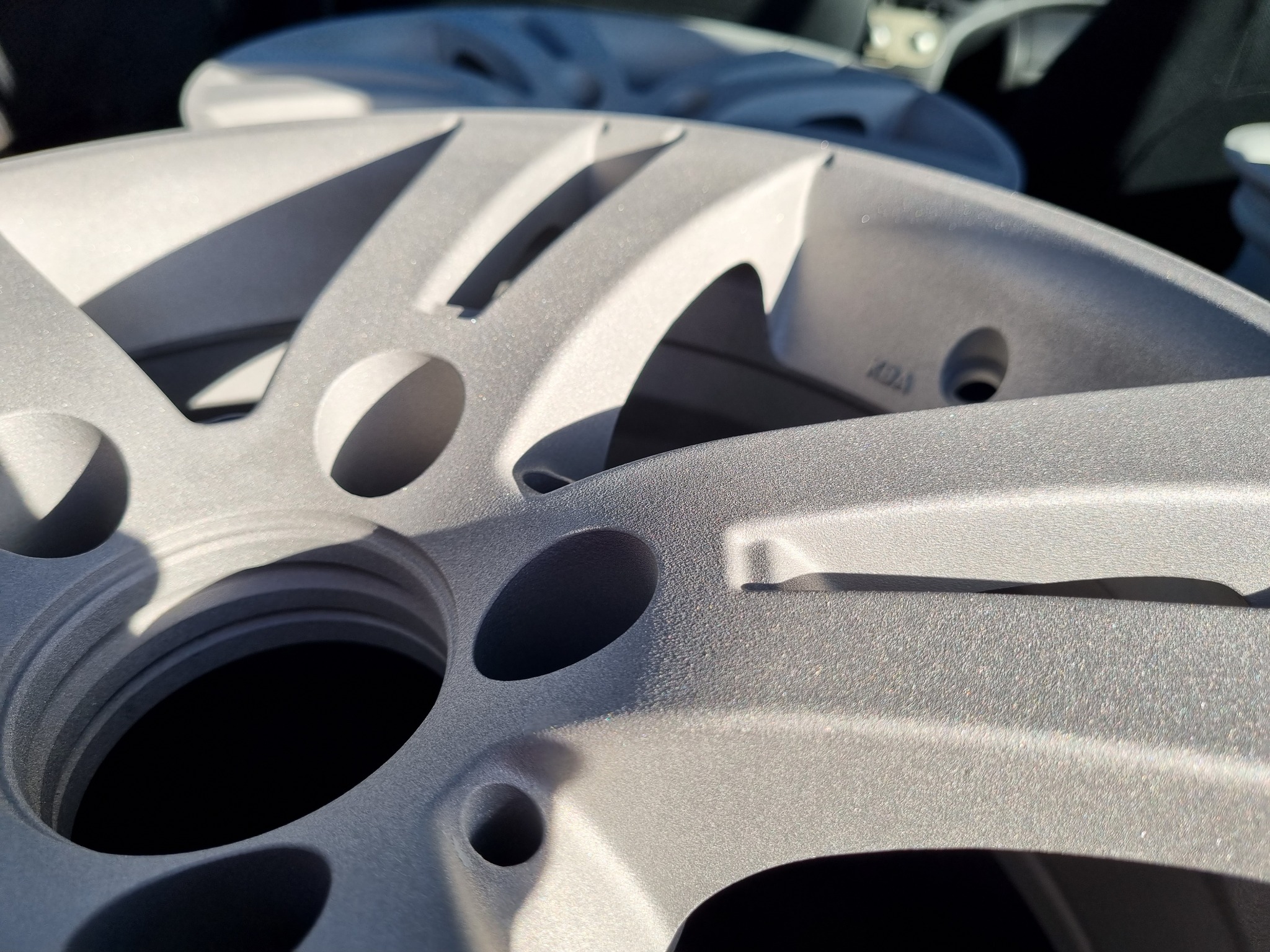 Szare felgi samochodowe po piaskowaniu i malowaniu proszkowym, widoczna chropowata faktura powierzchni