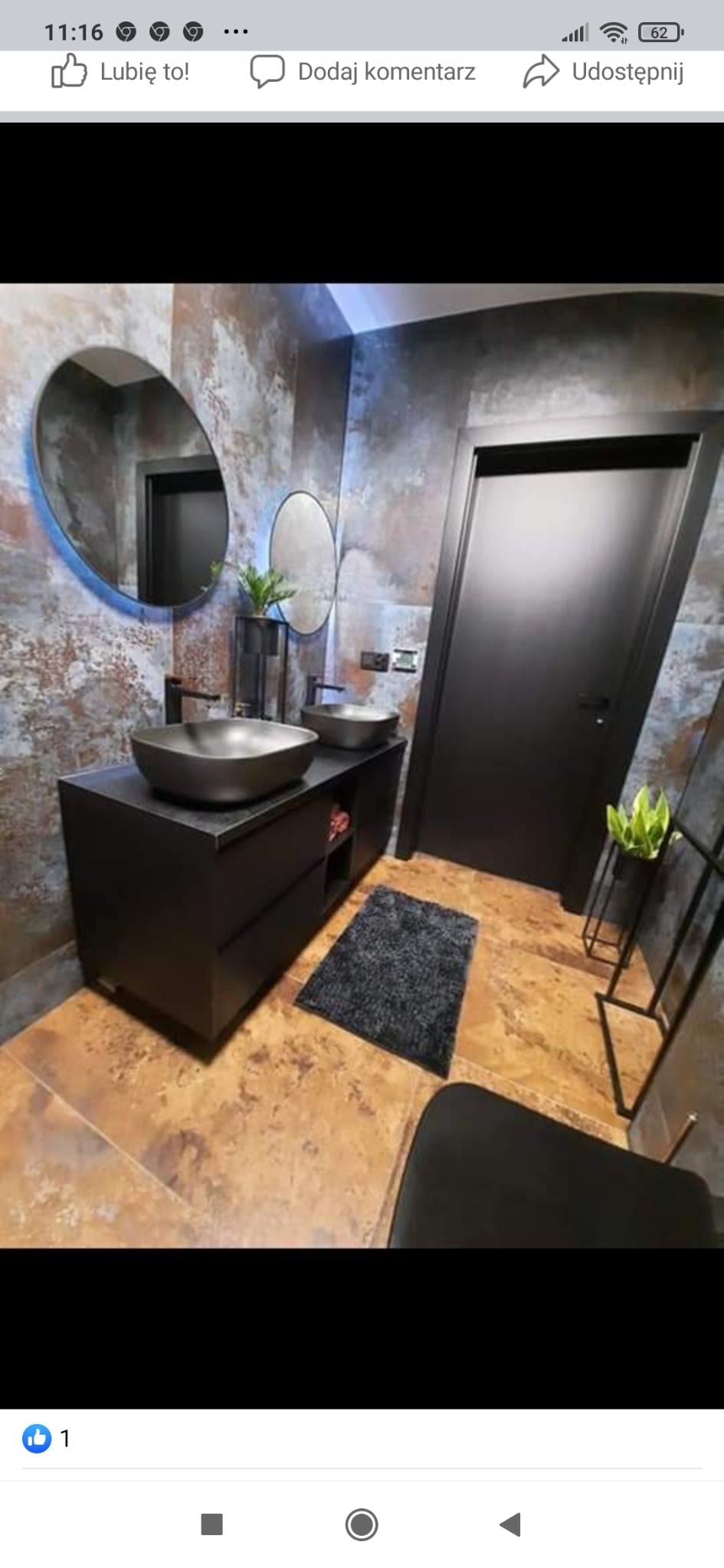 Nowoczesna łazienka z dwoma czarnymi umywalkami nablatowymi, owalnym lustrem z podświetleniem LED, czarnymi drzwiami i dekoracyjną ścianą w odcieniach brązu i szarości.