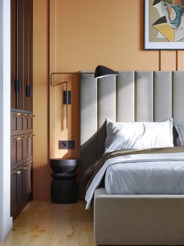 Nowoczesna sypialnia z łóżkiem z tapicerowanym wezgłowiem, czarną lampką nocną i szafką nocną w kształcie klepsydry, na ścianie abstrakcyjny obraz w ramie.