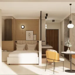 Wnętrze kawalerki z wydzieloną strefą sypialną, aneksem kuchennym i miejscem do spożywania posiłków. Widoczny telewizor na ścianie, łóżko z zagłówkiem, okrągły stół z krzesłem i kanapa w kolorze...