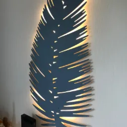 Dekoracyjna lampa ścienna LED w kształcie pióra, podświetlona ciepłym światłem, zamontowana na białej ścianie o delikatnej strukturze, obok routera.