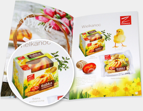 Rozkładówka katalogu z wielkanocnymi babkami marki Zaskocz, prezentująca opakowania i aranżacje z pisklęciem, jajkami i narcyzami.