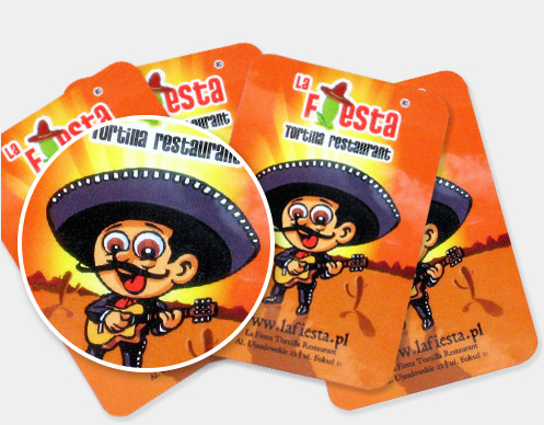 Stos pomarańczowych ulotek z zaokrąglonymi rogami, z kreskówkowym wizerunkiem meksykańskiego muzyka w sombrero i nazwą restauracji 'La Fiesta Tortilla restaurant'.
