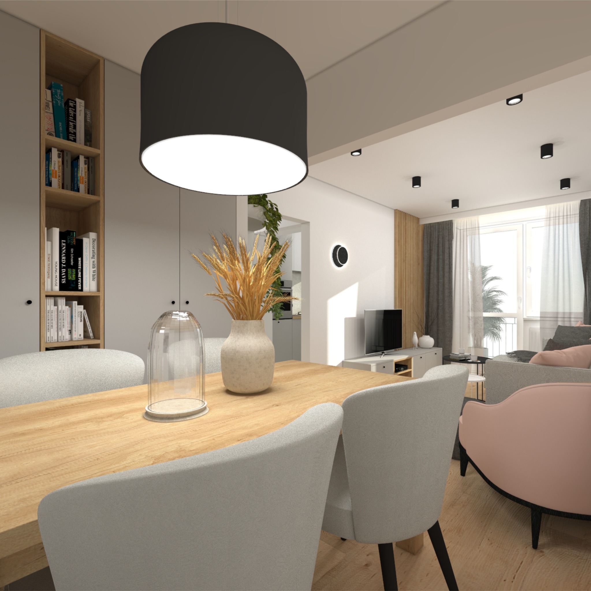 Wnętrze mieszkania: stół z drewnianym blatem, szare krzesła, wazon z suchymi trawami, czarna lampa wisząca, regał z książkami, widok na salon z różową sofą.