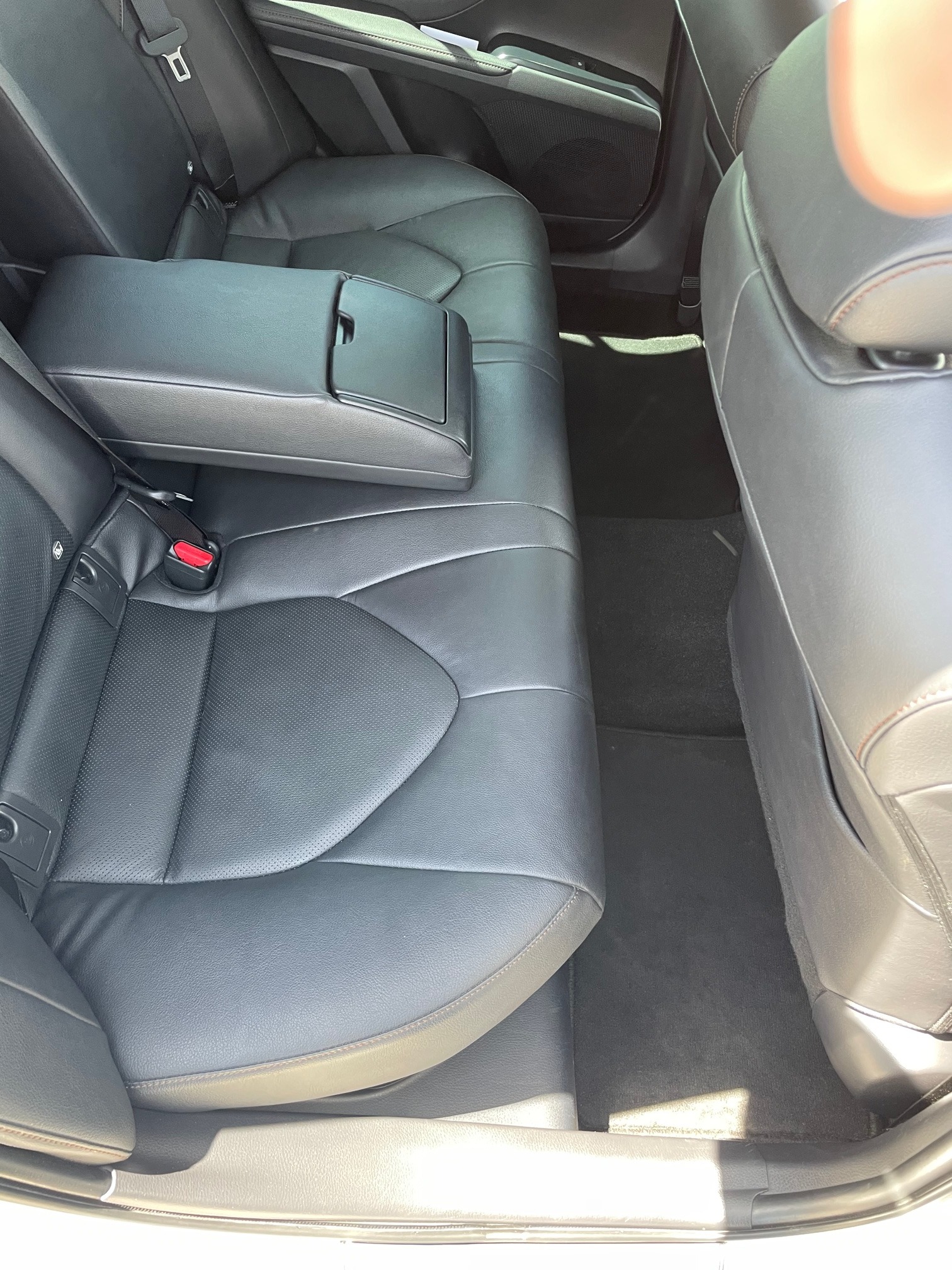 Wnętrze samochodu z czarną skórzaną tapicerką tylnych siedzeń, z rozkładanym podłokietnikiem pośrodku, widoczne mocowania ISOFIX.