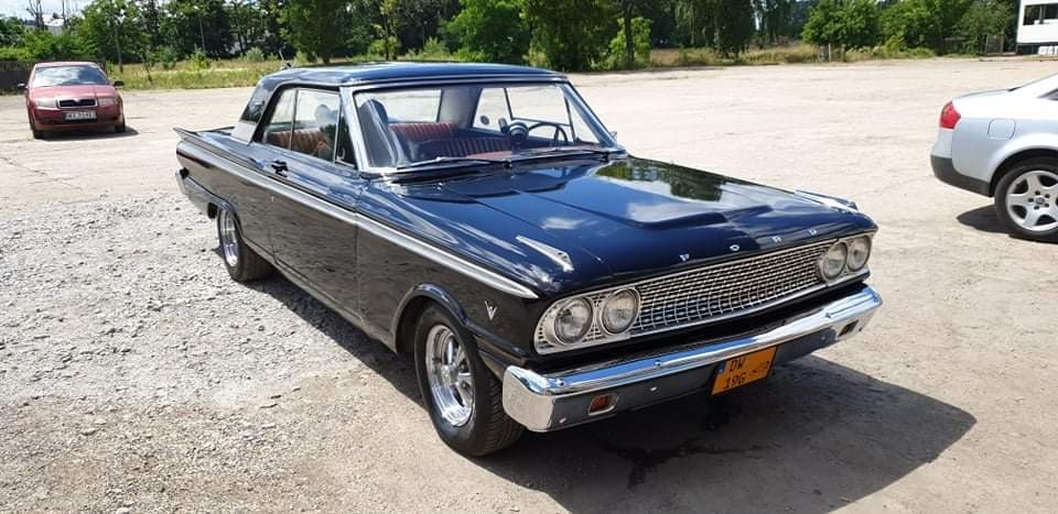 Czarny Ford Fairlane 500 z 1964 roku na parkingu, widok z przodu, tablica rejestracyjna DW 196.