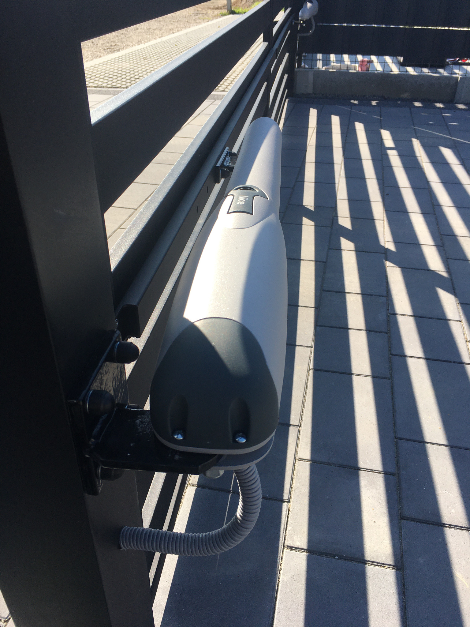 Montaż napędu Nice Wingo 2024 do bramy dwuskrzydłowej, prowadzenie przewodów w słupkach.