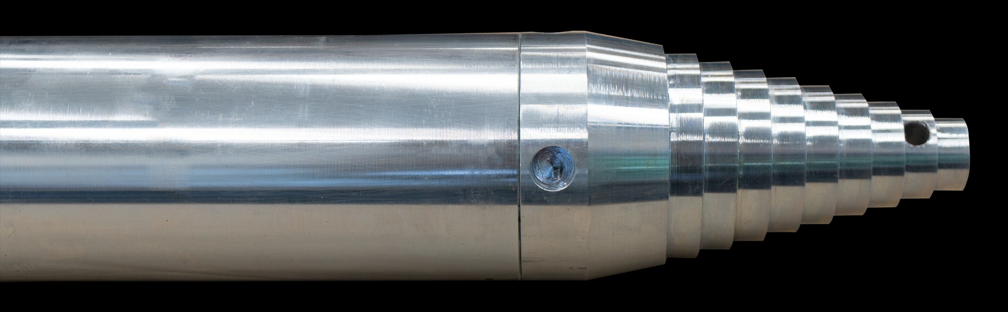 Chromowany, teleskopowy cylinder hydrauliczny z widocznym otworem montażowym i śladami obróbki skrawaniem na powierzchni.