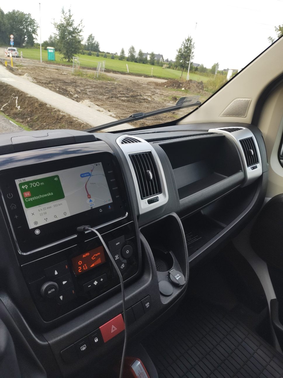 Wnętrze samochodu dostawczego z nawigacją ustawioną na Częstochowę, widok na deskę rozdzielczą i otoczenie za szybą.