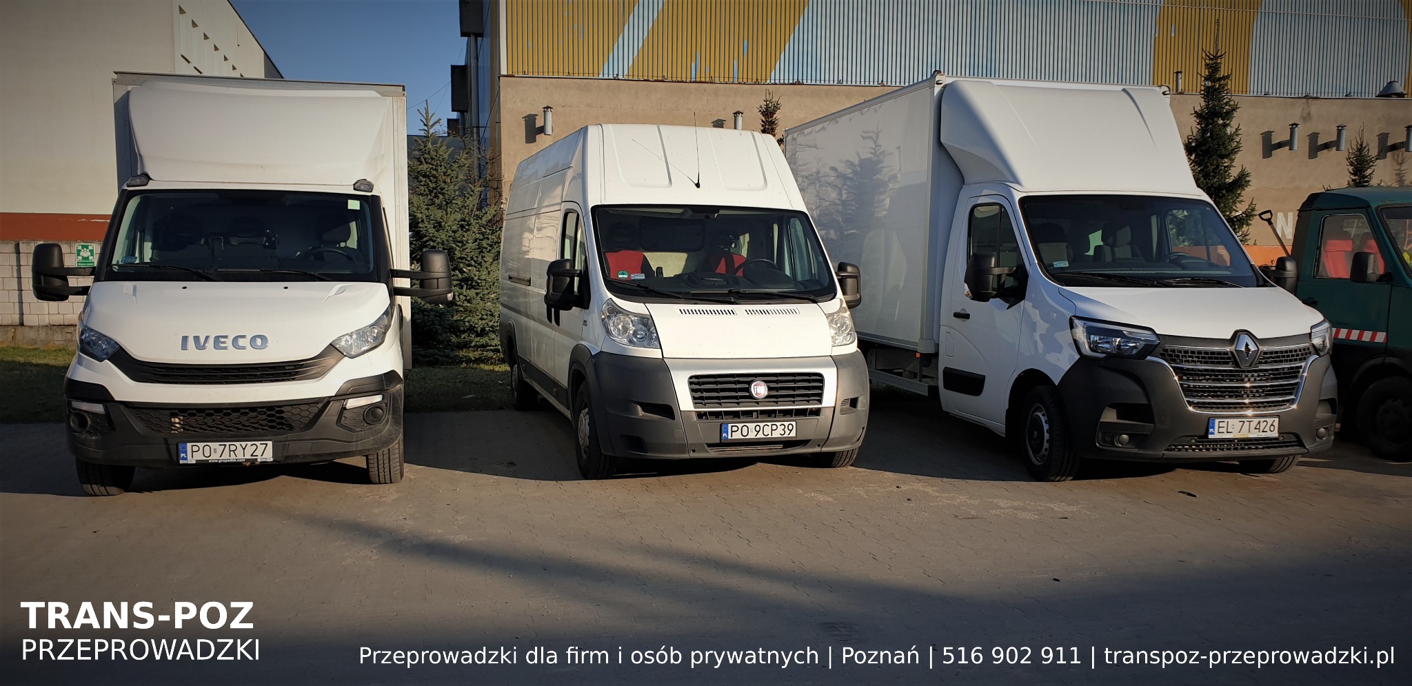 Trzy białe busy transportowe różnych marek (Iveco, Fiat, Renault) zaparkowane obok siebie na placu, z zielonym busem w tle, przed budynkiem o żółto-szarym wykończeniu.