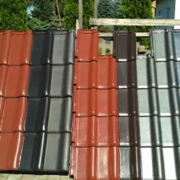 Ekspozycja dachówek ceramicznych w różnych kolorach, ułożonych obok siebie na zewnątrz, z widocznymi detalami faktury i połysku.
