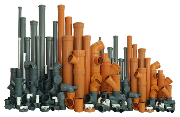 Asortyment rur i kształtek kanalizacyjnych PVC w odcieniach szarości i pomarańczy, ułożonych na białym tle.