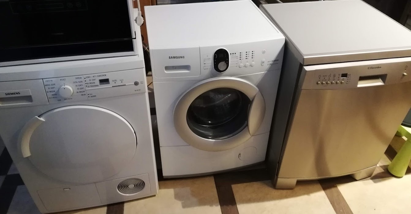 Ustawione obok siebie: suszarka Siemens, pralka Samsung i zmywarka Electrolux, wszystkie w kolorze białym lub srebrnym, na podłodze z płytek w odcieniach brązu.