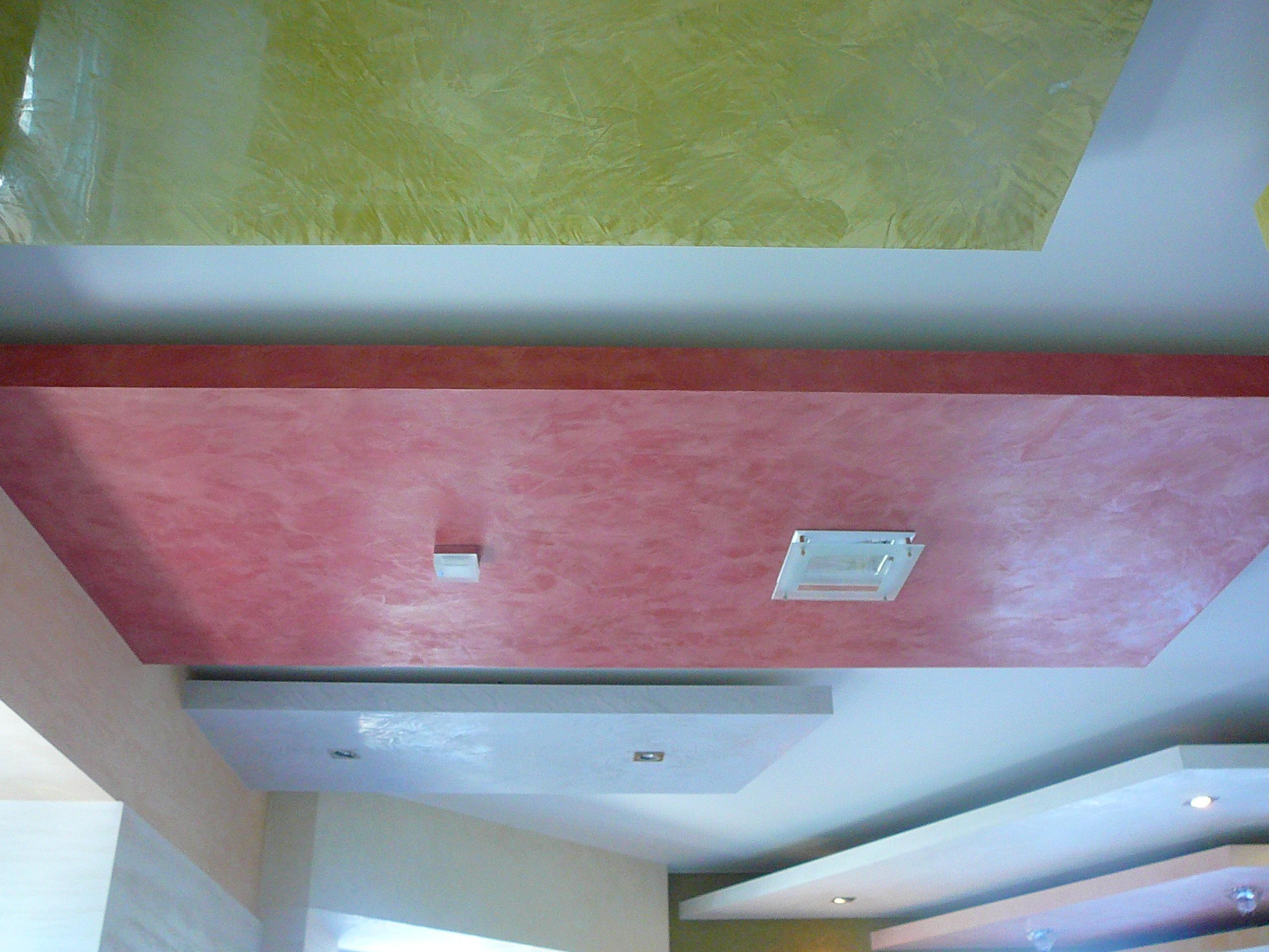 Dekoracyjny sufit z różowymi i żółtymi panelami, oświetleniem punktowym i kwadratową lampą.