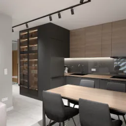 Nowoczesna kuchnia z czarnymi szafkami i drewnianymi frontami, oświetleniem punktowym i szklaną witryną, stół z szarymi krzesłami, widok z salonu.