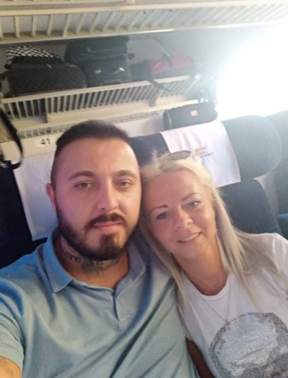 Selfie mężczyzny z tatuażem na szyi i blondynki w pociągu PKP, bagaże na półce powyżej.