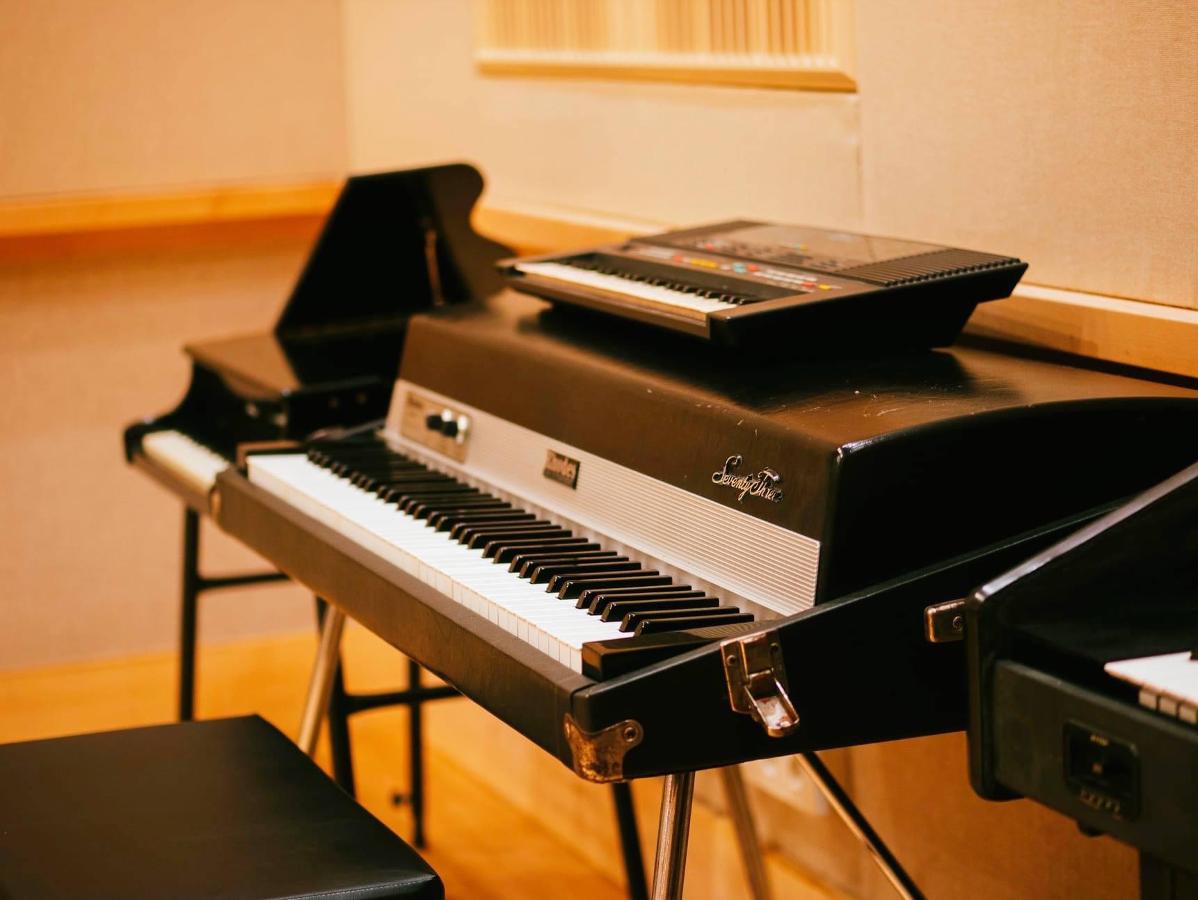 Elektryczne pianino Rhodes Seventy Three z dodatkowym keyboardem na wierzchu w pomieszczeniu z panelami akustycznymi.