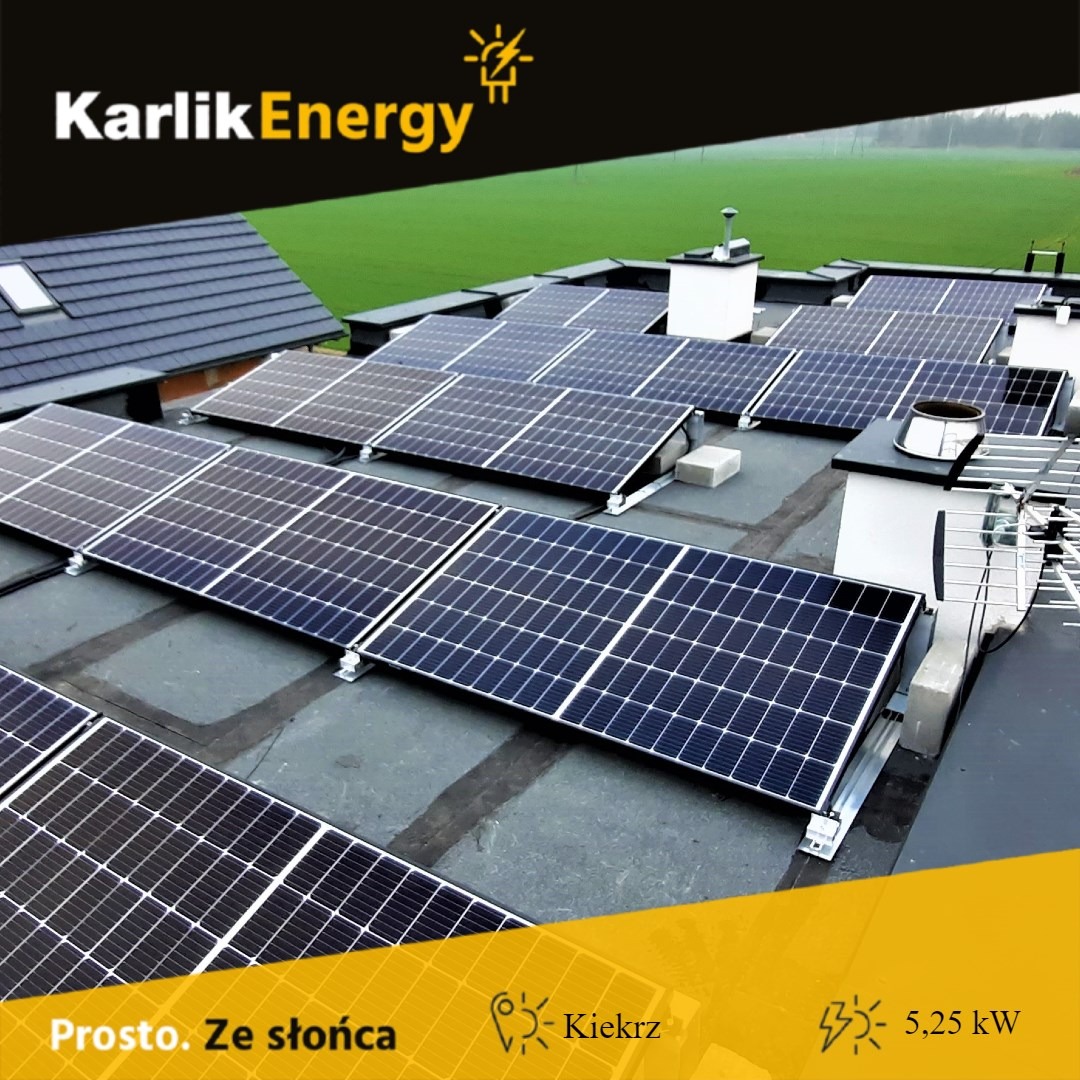 Instalacja paneli słonecznych na płaskim dachu z widocznym logo firmy Karlik Energy, z zielonym polem w tle.