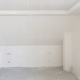 Karpińscy Firma Budowlana - Poddasze po remoncie: białe ściany, wykończona zabudowa sufitu, gładkie powierzchnie gotowe do dalszych prac wykończeniowych, widoczne gniazdka elektryczne.