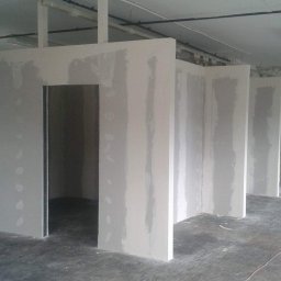 Karpińscy Firma Budowlana - Wnętrze z nowymi ścianami działowymi z płyt gipsowo-kartonowych, widoczne szpachlowanie łączeń, surowy betonowy podkład, instalacje pod sufitem.