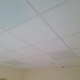 Sufit podwieszany z białych paneli rastrowych w pomieszczeniu w Lisewo, widoczny czujnik dymu.