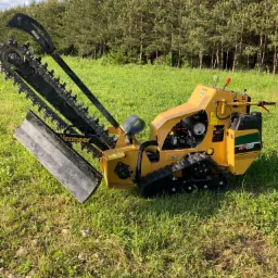 Żółta frezarka łańcuchowa Vermeer RTX250 na gąsienicach, stojąca na trawiastym terenie z widocznym lasem iglastym w tle, uchwycona w słoneczny dzień.