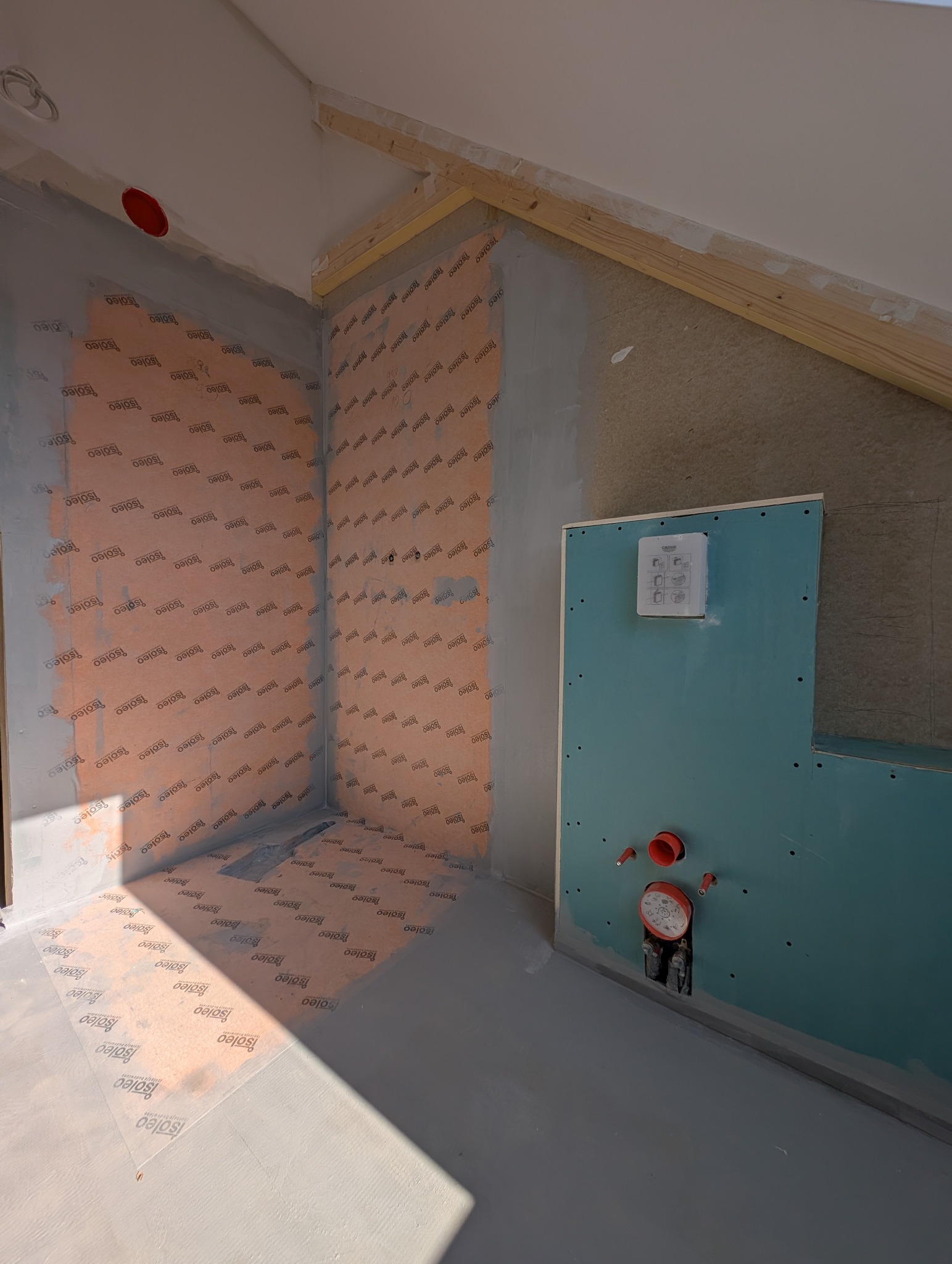 Przygotowanie do hydroizolacji w łazience na poddaszu: folia w płynie na ścianach i podłodze, płyta GK na stelażu podtynkowym, widoczne przyłącza wod-kan.