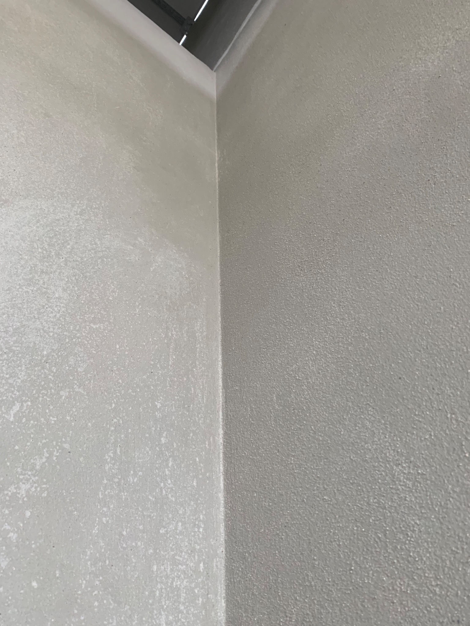 Świeżo nałożony, jasny tynk cementowo-wapienny na ścianie wewnętrznej, widoczny narożnik i fragment sufitu.