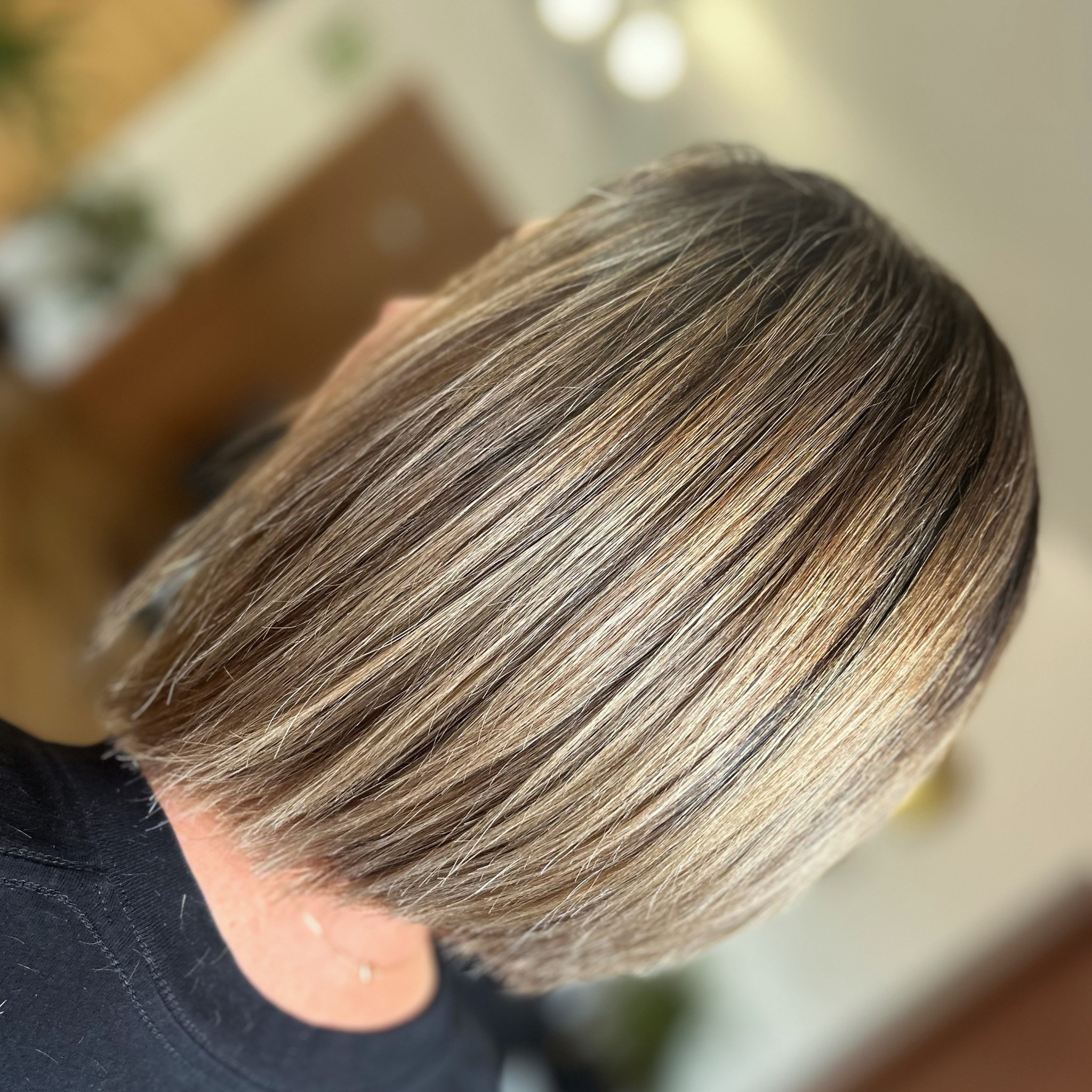 Krótkie, proste włosy z koloryzacją sombre, widoczne z góry, z lekkim połyskiem na dobrze oświetlonych pasmach.