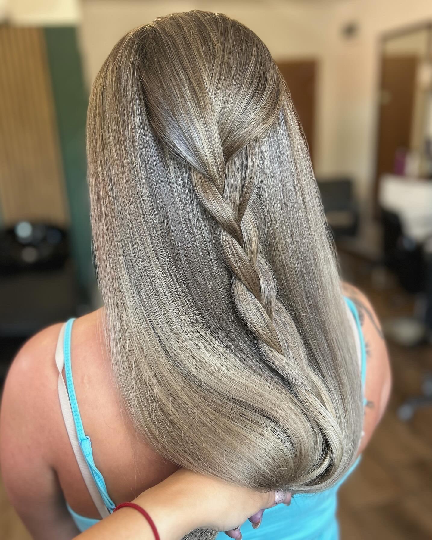 Długie, popielate włosy z zaplecionym warkoczem na środku, widok z tyłu, fragment tatuażu na ramieniu