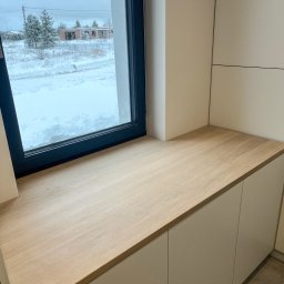 Mazi-Wood - Jasny, dębowy blat przy oknie z widokiem na zasypany śniegiem krajobraz i budowę w oddali, zamontowany nad szafkami.