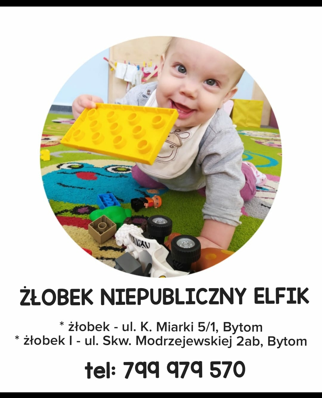 Uśmiechnięte niemowlę na brzuchu bawi się żółtą klockową płytką na kolorowym dywanie z zabawkami.