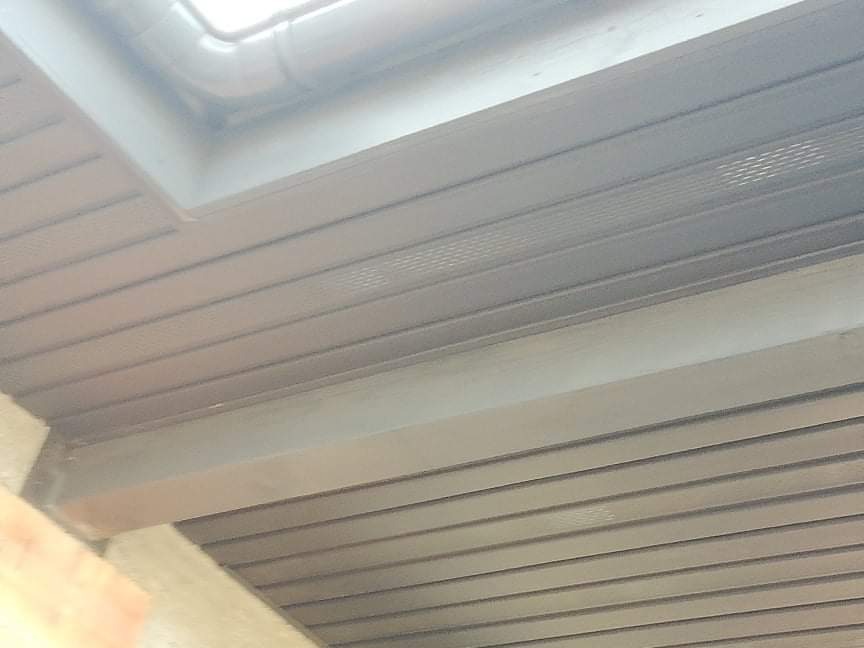 Widok od dołu na podbitkę dachową z widocznym oknem dachowym i fragmentem muru.