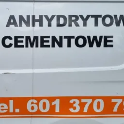 Reklama na boku białego samochodu dostawczego z napisem 'Posadzki Anhydrytowe. Podłoża Cementowe.' oraz numerem telefonu w kolorze pomarańczowym.