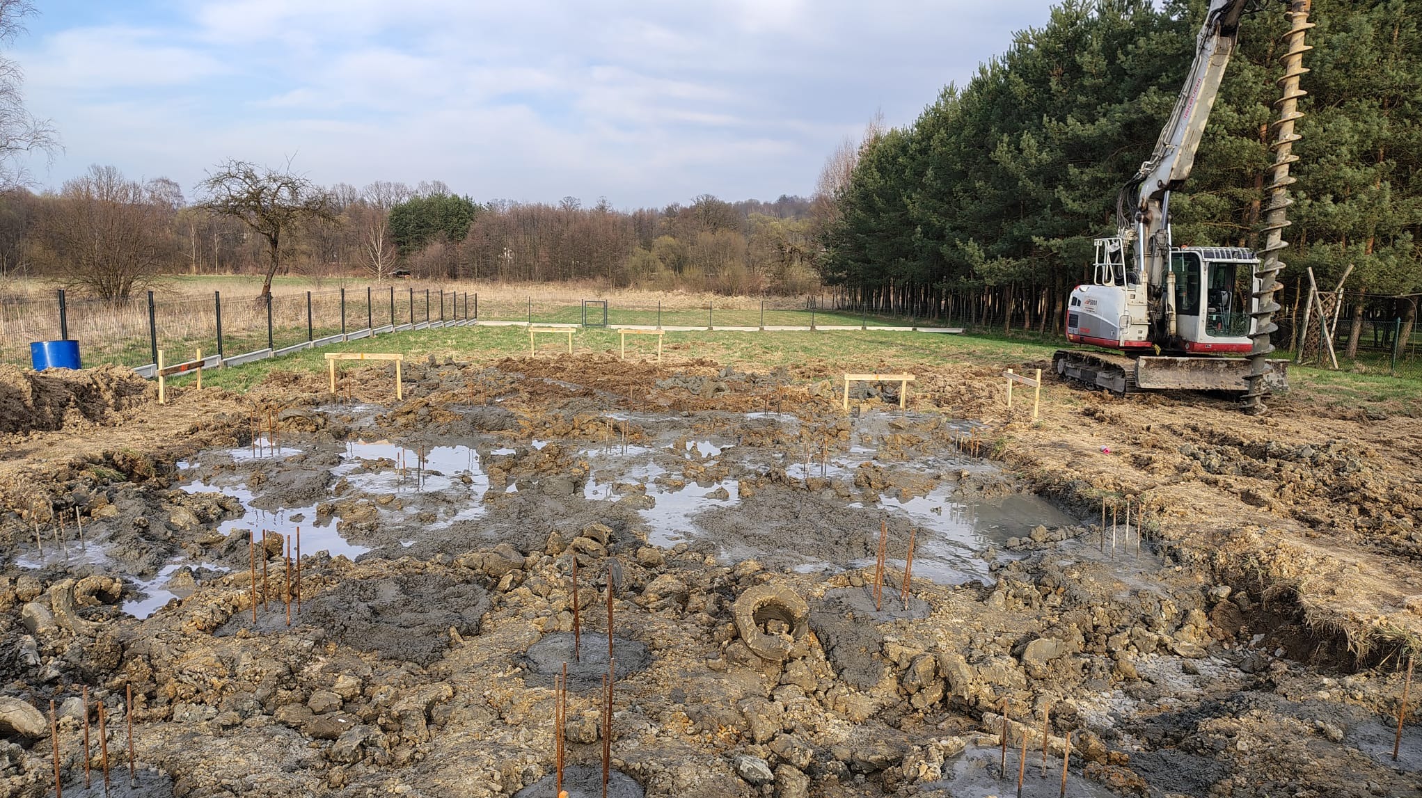 Wykonywanie mikropali iniekcyjnych pod płytę fundamentową na gruncie nienośnym. W tle widoczna wiertnica i ogrodzenie terenu budowy.