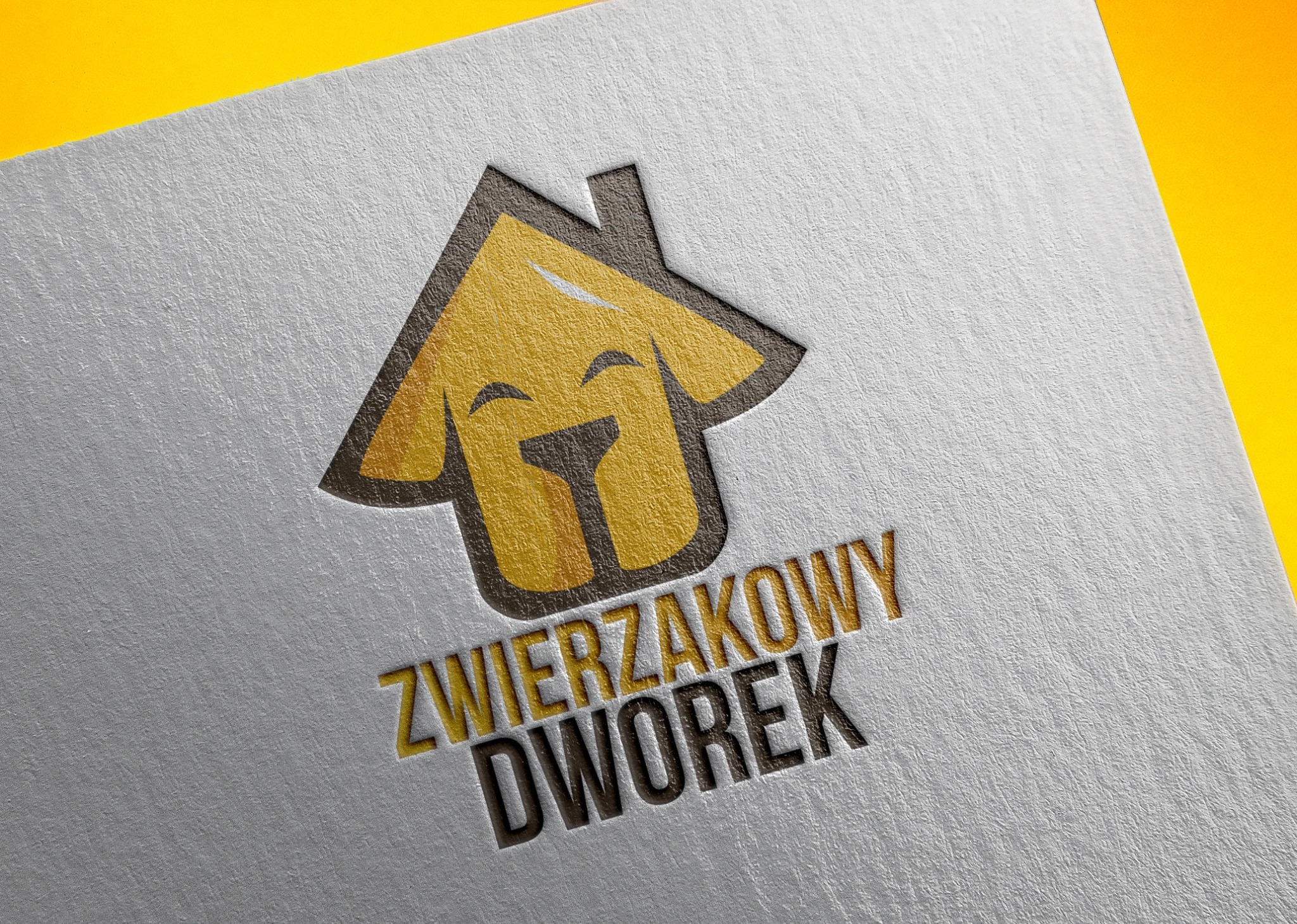 Logo firmy 'Zwierzakowy Dworek' przedstawiające stylizowany dom z wizerunkiem psa, wytłoczone na teksturowanym, srebrzystym papierze z żółtym tłem.