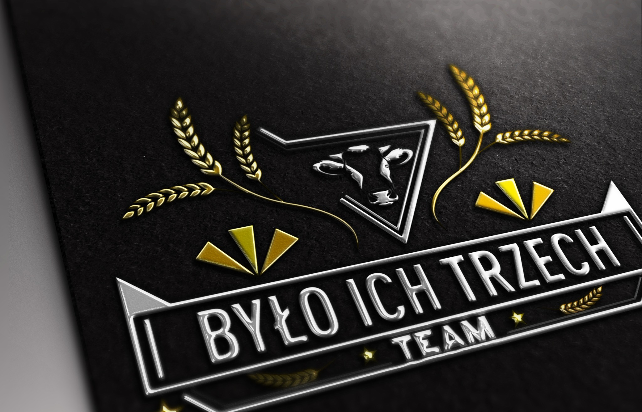 Eleganckie logo z motywem zwierzęcym i zbożowym na czarnym teksturowanym tle, z metalicznymi elementami i napisem 'Było Ich Trzech TEAM'.
