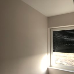 Bartosz Guz - Świeżo pomalowane wnętrze pokoju w odcieniach beżu, z oknem z żaluzjami i grzejnikiem.