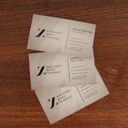 Stos wizytówek Kancelarii Radcy Prawnego Joanna Zielińska na drewnianym biurku, z widocznym logo i danymi kontaktowymi.