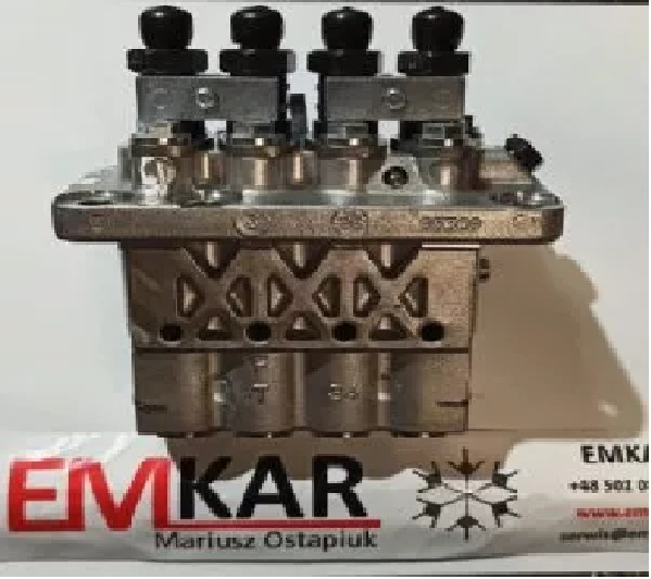 Metalowy blok z czterema zaworami, widoczne oznaczenia i logo firmy EMKAR na wizytówce w tle.