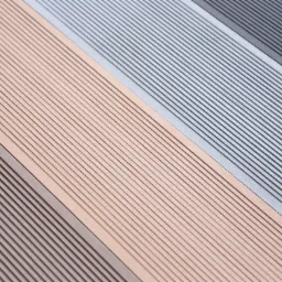 Kompozytowe deski tarasowe w odcieniach brązu, beżu, szarości i grafitu, ułożone diagonalnie, prezentujące fakturę ryflowaną.