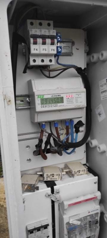 Otwarta skrzynka elektryczna z bezpiecznikami, licznikiem energii i okablowaniem w Mikołowie. Widoczny wyświetlacz licznika z odczytem.