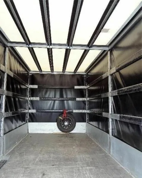 Wnętrze pustej przestrzeni ładunkowej busa z zamocowanym kołem zapasowym na tylnej ścianie.