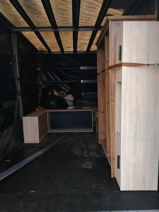 Meble zabezpieczone pasem w przestrzeni ładunkowej, gotowe do przewozu.