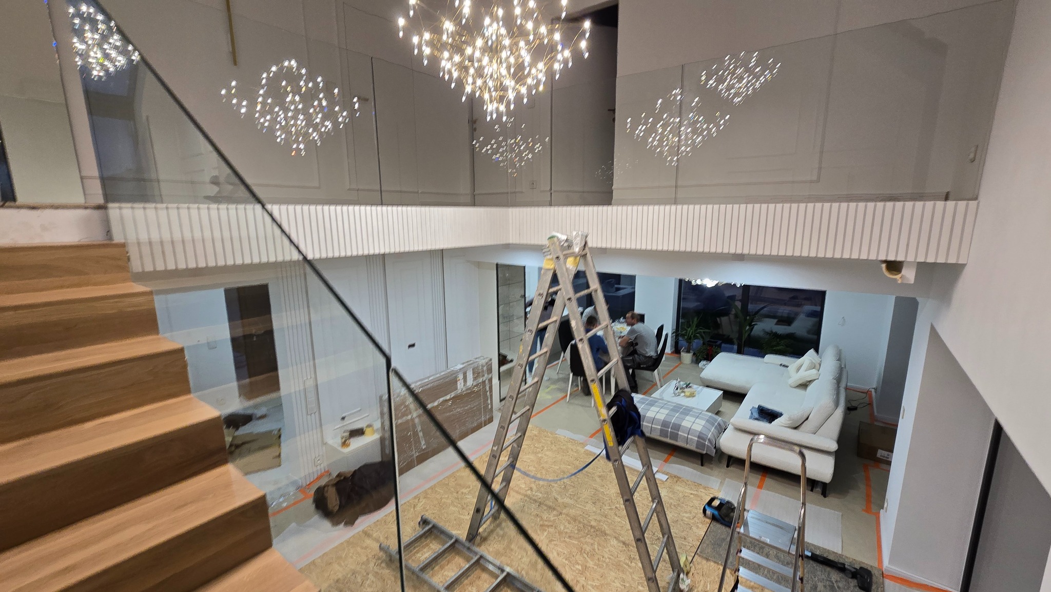 Montaż drewnianych schodów z balustradą szklaną w nowoczesnym wnętrzu. Widoczne schody, balustrada, drabina i ekipa montażowa. Górne oświetlenie w stylu glamour.